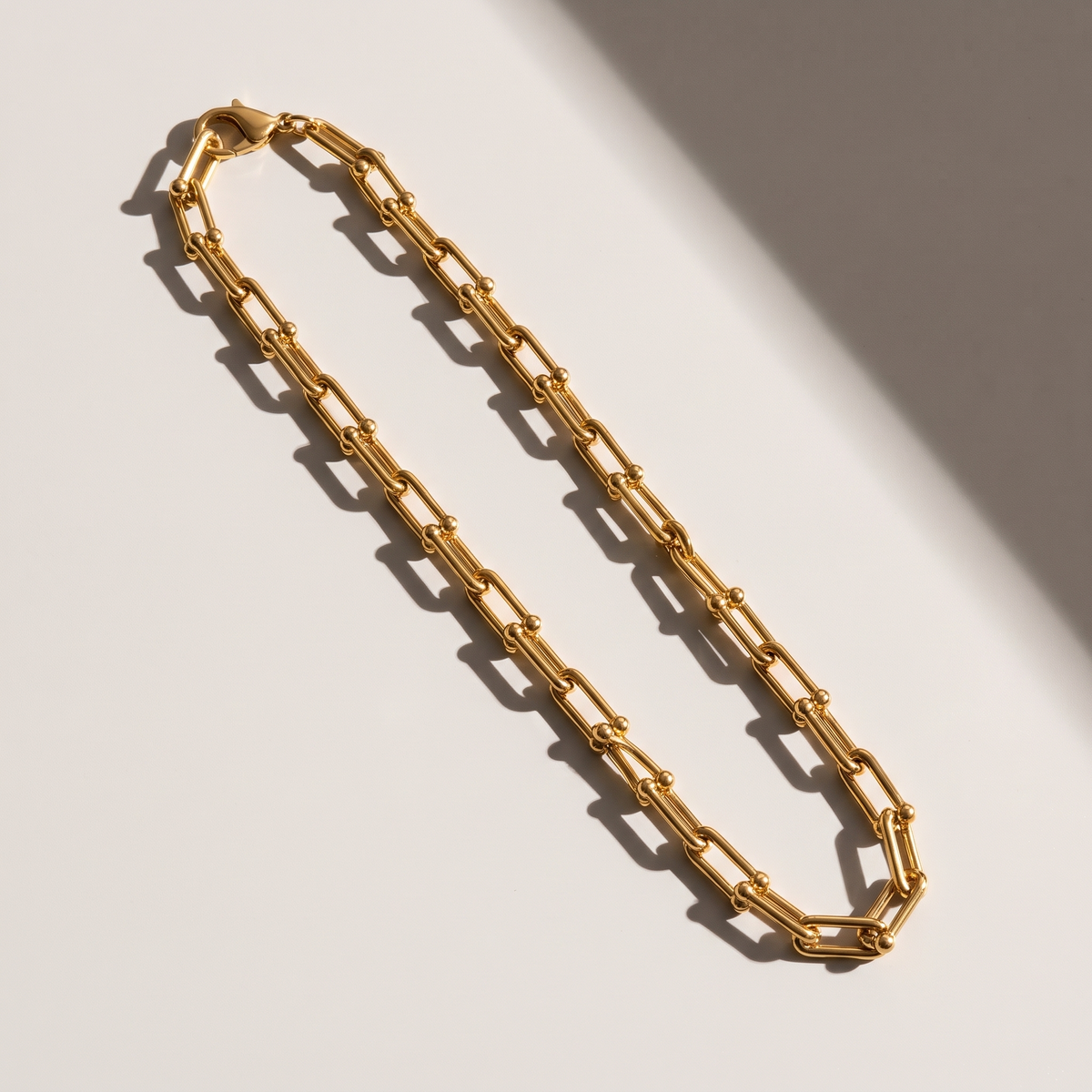 Vera Paperclip Necklace in gold finish - ARWELY editorial still life with a hard shadow
