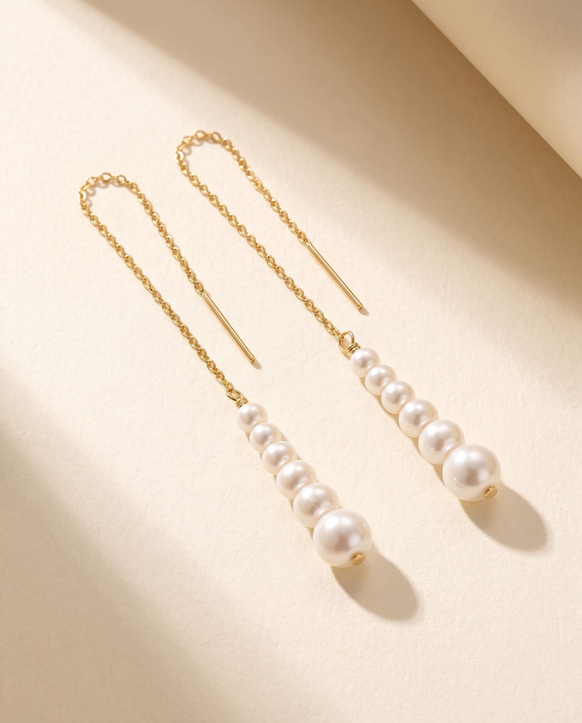 Cascade Pearl Threaders in gold - ARWELY, the pair laid flat showing the graduated line of pearls
