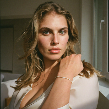 Rivière Tennis Bracelet worn by a model in a bright apartment, hand raised near the collarbone