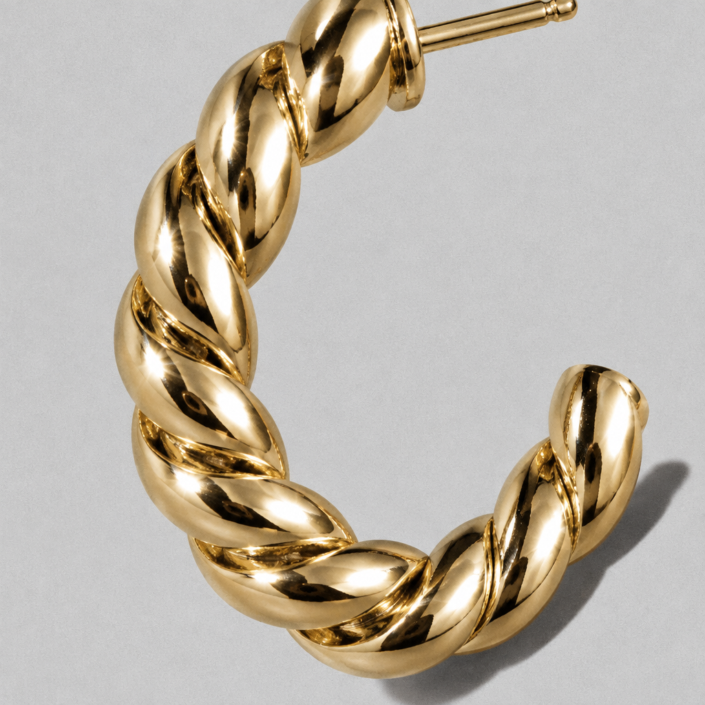 Arc Hoop Earring close up on a diagonal, hard light across the twist