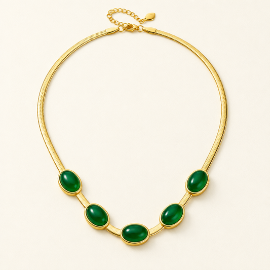 Cléo Necklace, five oval green cabochons set along a flat gold snake chain, on a warm off-white background