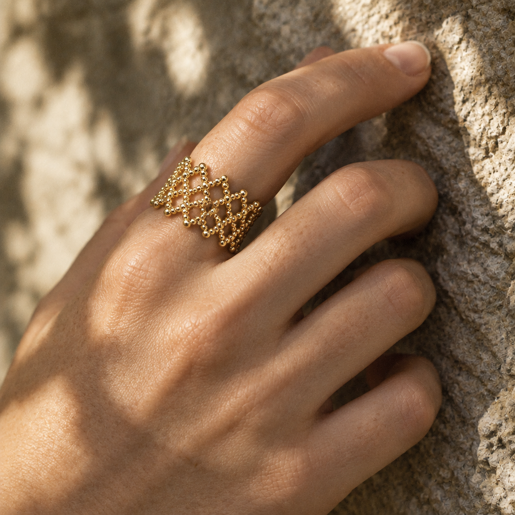 Tressa Open Ring worn on the hand against a stone wall in dappled light