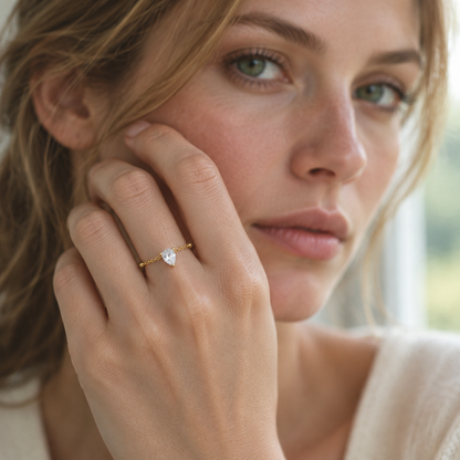 Rosée Drop Ring in gold worn, hand raised near the face in window light