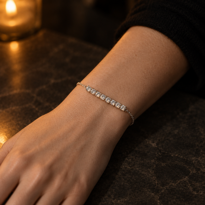 Orbit Bar Bracelet in silver worn on the wrist, seen from above in evening candlelight
