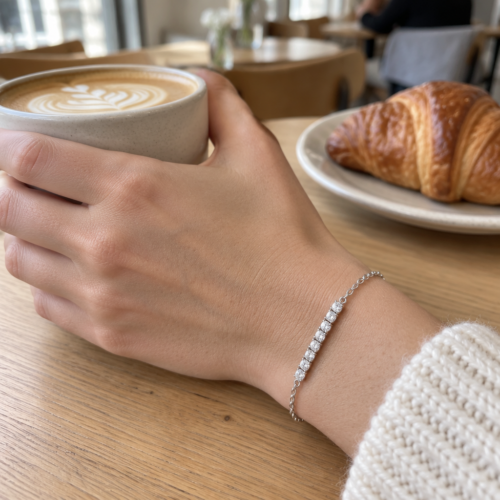 Orbit Bar Bracelet in silver worn in a café, hand around a coffee cup in window light